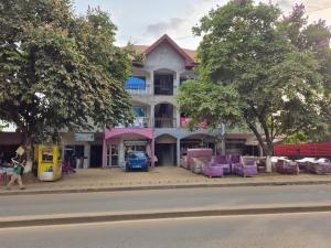 a building on the side of a street with purple chairs at G and E Guesthouse in Kumba