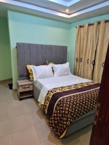 a bedroom with a large bed with a gray headboard at G and E Guesthouse in Kumba