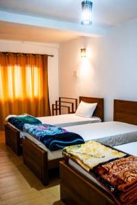 a bedroom with two beds and a window at MGM Daisy Resorts in Nuwara Eliya