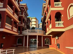 a courtyard of a building with red walls and white balconies at Apartamentos Amy 3 con vista a mar in Palos de la Frontera