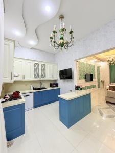 a large kitchen with blue cabinets and a chandelier at Novxanı Villa in Baku