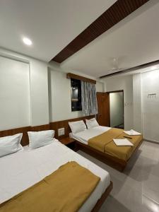 a hotel room with two beds and a mirror at Hotel Sumeet Palace in Shirdi