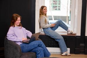 two women sitting in chairs with a laptop at Capsule Residence in Montreal