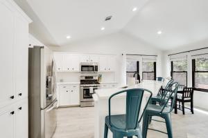 a kitchen with white cabinets and a table with green chairs at Woodacre Cottage in Wimberley