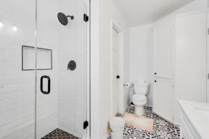 a white bathroom with a shower and a toilet at Woodacre Cottage in Wimberley