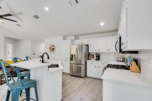 a white kitchen with white cabinets and blue chairs at Woodacre Cottage in Wimberley