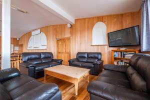 a living room with leather furniture and a flat screen tv at Omori Lodge in Tokaanu