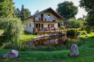 a house with a pond in front of it at Beachside Guest House Strautini in Plieņciems