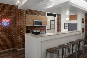 a kitchen with a brick wall and a bar with stools at The Haas, Trademark Collection by Wyndham in Los Angeles