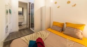 a bedroom with a bed with yellow and orange pillows at Escapade studio centre ville Rodez in Rodez +8 photos
