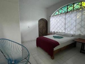 a bedroom with a bed with a window and a chair at Casa Malinalli in Zihuatanejo