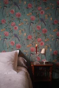 a bedroom with a floral wallpaper with a bed and a candle at La Maison Saint Aignan in Saint-Aignan