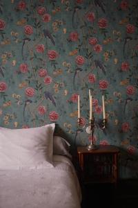 a bedroom with a floral wallpaper with a bed and candles at La Maison Saint Aignan in Saint-Aignan