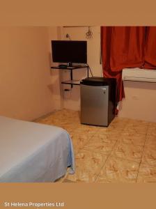 a room with a bed and a desk with a television at Triple K Complex in Kelly Village