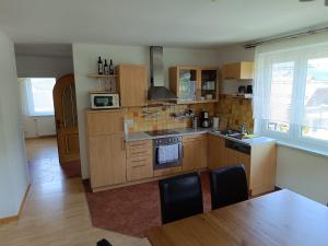 a kitchen with wooden cabinets and a table with chairs at Große Ferienwohnung im Rosental ideal für 4 bis 6 Personen mit Balkon und Garten in Maria Elend +9 photos