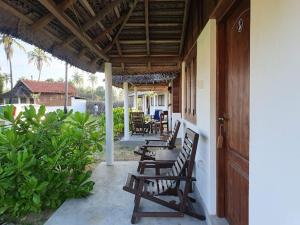 a porch with chairs and a table on a house at windy beach kite resort in Kalpitiya