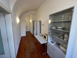 a kitchen with white cabinets and a wooden floor at Artillery Barracks Accommodation in Terezín