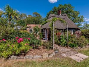 an old house with a thatched roof in a garden at 1 Bed in Brockenhurst oc-78767 in Beaulieu