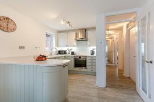 a kitchen with white cabinets and a clock on the wall at 2 Bed in Woolacombe oc-bsnug in Woolacombe