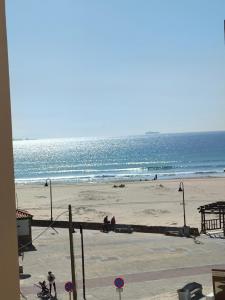 a beach with people sitting on the sand and the ocean at Apartamento Lances playa tarifa in Tarifa