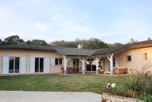 a house with a patio and a yard at Villa A Macchia, piscine et vue sur Bonifacio in Bonifacio