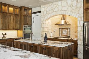 a kitchen with wooden cabinets and a stone wall at Big Red Chicken Estate in Wimberley