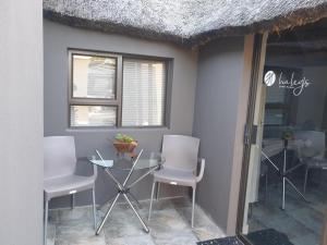 a glass table and chairs in a room at Haleys Guest House in Benoni