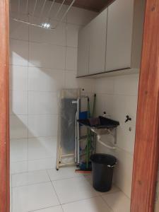 a small kitchen with white tile walls and a trash can at Bem Estar no Bom Ap 1 in Arapiraca +1 photo