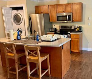 a kitchen with a counter with chairs and a refrigerator at Sunny 1BR by Galloping Goose in Victoria