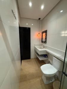 a white bathroom with a toilet and a sink at Casa Aurora Provetá - Ilha Grande in Angra dos Reis