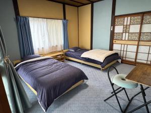 a bedroom with two beds and a table and a chair at Blue Art Satoyama Retreat in Ōasa