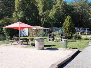 a picnic table with a red umbrella in a park at MOBIL-HOME n 95 in Barrême