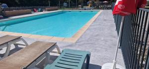 a swimming pool with a chair and a table and a red umbrella at MOBIL-HOME n 95 in Barrême