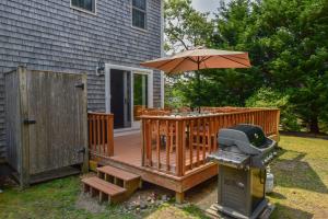 a wooden deck with an umbrella and a grill at Spacious w Beautiful Yard & Dogs Welcome in Harwich