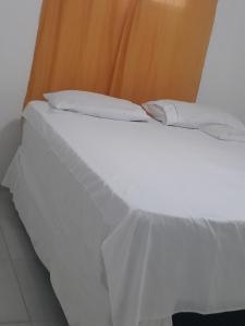 a white bed with white sheets and pillows at Pé na praia - Barraca da Márcia in Paracuru