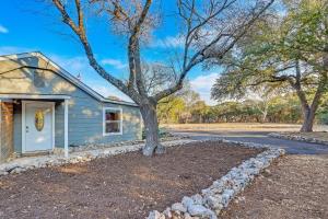 a house with a tree next to a road at Bungalow on the Bluff in Fischer