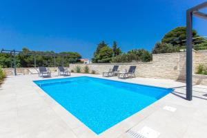 a swimming pool with blue water in a yard at Villa Ilenia in Murter