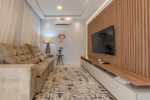 a living room with a couch and a flat screen tv at Apartamento 2 suítes C/Piscina in Bombinhas