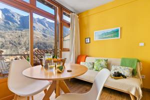 a living room with a table and chairs and a window at Apto rurales y habitaciones MONTE CAORU - CABRALES apartahotel in Arenas de Cabrales