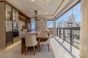 a kitchen with a table and chairs and a large window at Apartamento 2 suítes C/Piscina in Bombinhas