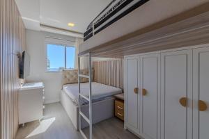a small bedroom with a bunk bed and a window at Apartamento 2 suítes C/Piscina in Bombinhas +23 photos