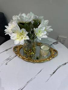 a vase with white flowers and a candle on a table at Secret Garden Suite in Gloucestershire