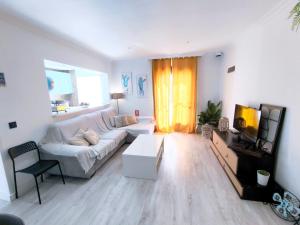 a living room with a white couch and a tv at Apartamento Lances playa tarifa in Tarifa