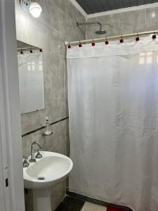a bathroom with a white shower curtain and a sink at La casita in Saladillo +15 photos
