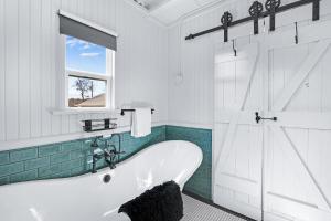 a white bathroom with a tub and a window at Caboose on the Square in Wimberley