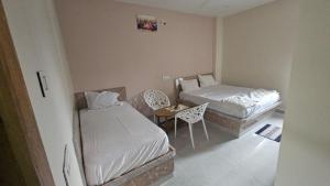 a bedroom with two beds and a table and chairs at hotel Mansion grand in Khammam