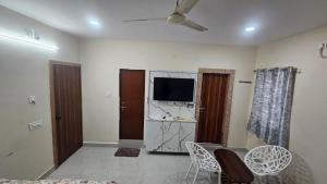 a living room with a flat screen tv and chairs at hotel Mansion grand in Khammam