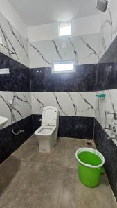 a bathroom with a toilet and a sink and a bucket at hotel Mansion grand in Khammam
