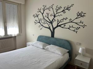 a bedroom with a tree stenciled on the wall at Casa Giulia in Santarcangelo di Romagna