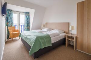 een slaapkamer met een bed, een stoel en een raam bij Appartementen de Strandloper in Bergen aan Zee